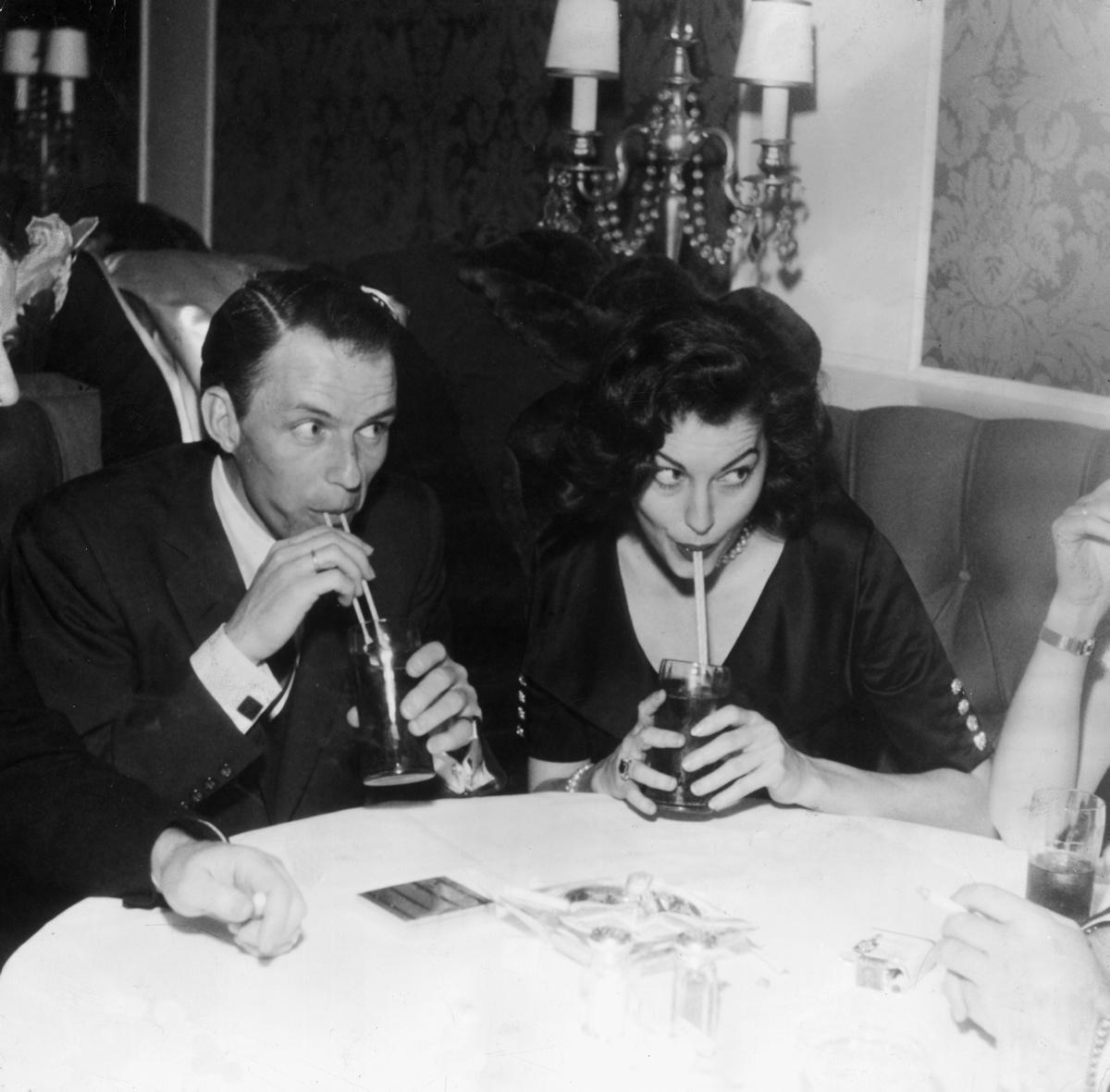 This cute photo shows Frank Sinatra and his wife at the time, Ava Gardner, sitting next to each other in a booth and sipping drinks with straws. Gardner was Sinatra's second wife and they were married from 1951-1957.