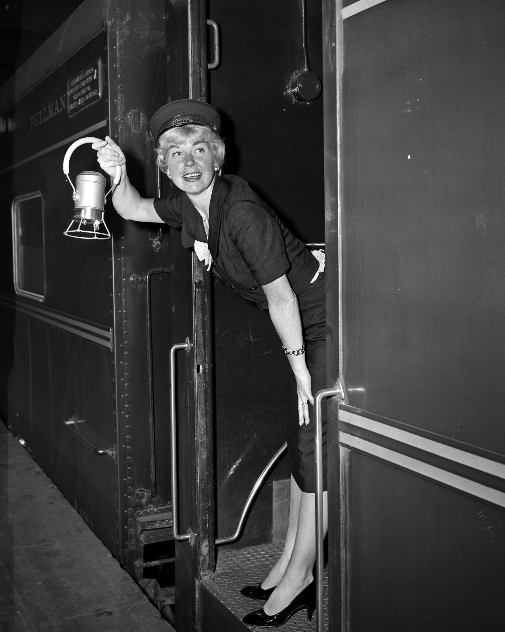 Doris Day alights at Penn Station on May 22, 1958, in New York, after training in from the Coast. She's all done up as railroader by way of getting into the mood for her next film, 