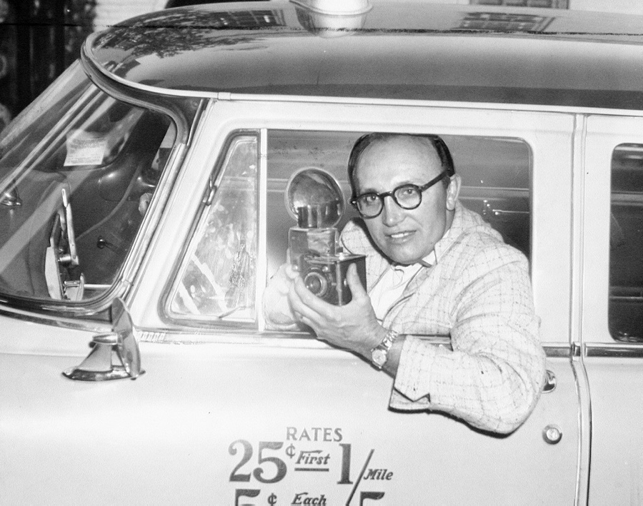 Smile for the taxi driver! Taxicab driver Eric Koberg poses with a camera in a cab. Take note of the cab's rates: a trip from Times Square to Battery Park would have cost about $1.35.