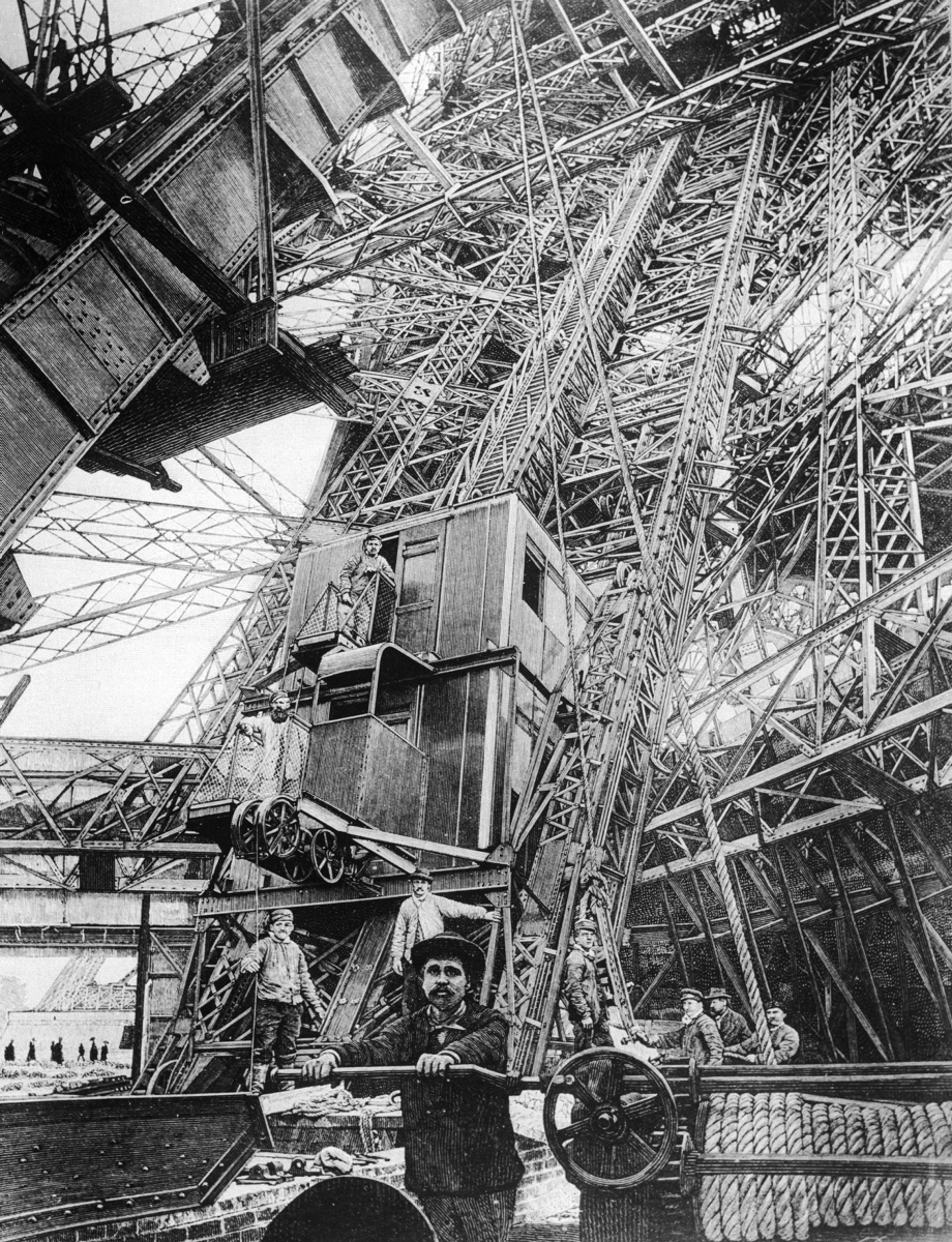 The tower was originally built to commemorate the French Revolution as the centerpiece of the 1889 World's Fair, which marked the centennial of the revolution in 1789. Here, the elevator is shown at the first level of the Eiffel Tower, during its construction. Two of the original lifts are still in service today.